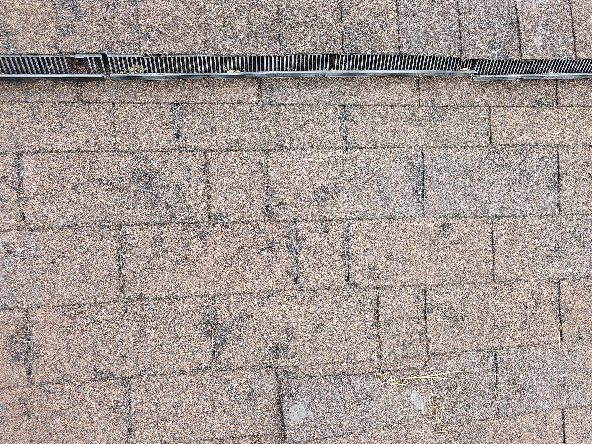 Close-up of worn and lifted asphalt shingles found during a D&S roof inspection